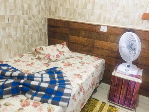 a small bedroom with a bed and a fan at Pousada Familia Aparecida in Aparecida