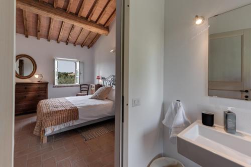 a bedroom with a bed and a bathroom with a sink at Podere Ferranino at Ville Ferrano in San Giovanni dʼAsso