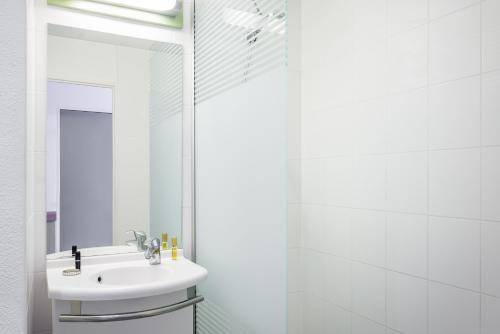 a white bathroom with a sink and a mirror at ibis budget Antwerpen Centraal Station in Antwerp