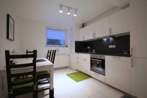 a kitchen with white cabinets and a table with a green rug at Wohnung Tannengrün in Schmitten