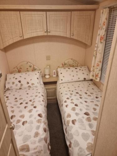 two twin beds in a small room at palm grove 16 in Skegness