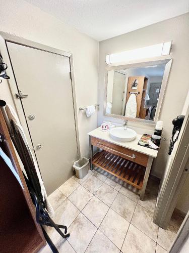 a bathroom with a sink and a mirror at Days Inn & Suites by Wyndham Arlington Near Six Flags in Arlington