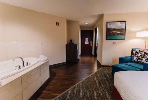 um quarto de hotel com uma banheira, uma cama e uma cadeira em The Portlander Inn and Marketplace em Portland