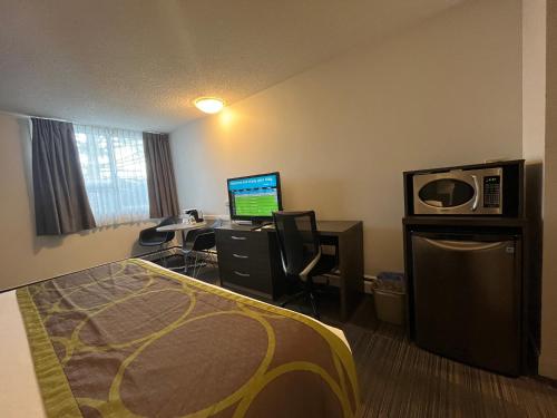a hotel room with a bed and a desk with a computer at Super 8 by Wyndham Macleod Trail Calgary in Calgary