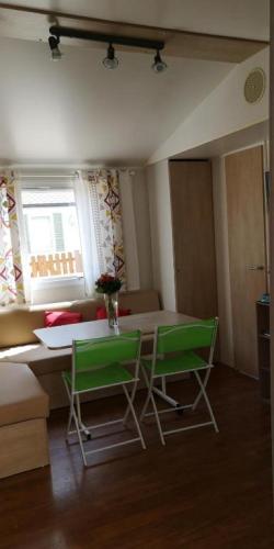 une chambre avec une table et deux chaises vertes dans l'établissement SHAKA Aum, à Sigean