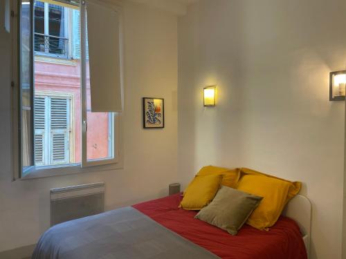 a bedroom with a bed with yellow pillows and a window at In the heart of Old Nice - 2min. from Cours Saleya and Promenade des Anglais in Nice