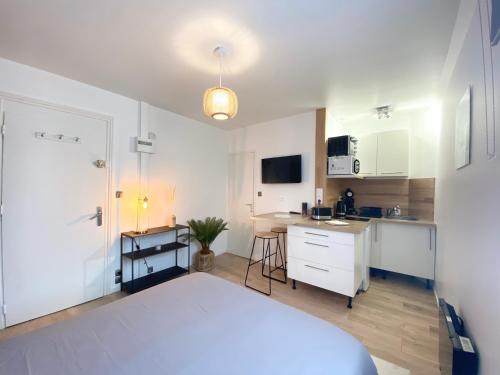 Un dormitorio con una cama blanca y una cocina. en LE GENTILHOMME - Studio - Entrée autonome - Plein centre historique, en Quimper