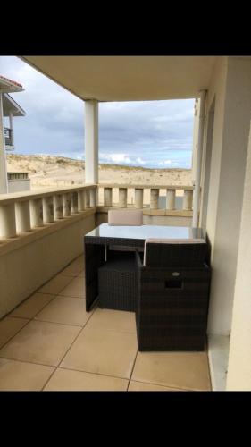 d'un balcon avec une table et une vue sur la plage. dans l'établissement T2, bord de plage et piscine, à Biscarrosse