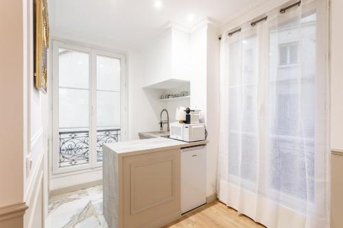 una cucina bianca con forno a microonde e finestra di SUITE RAPHAEL Tour Eiffel a Parigi
