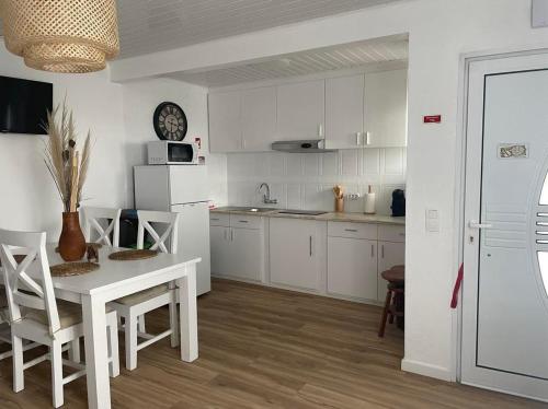 a kitchen with white cabinets and a table and chairs at Tesouro do Atlântico in Ponta Delgada