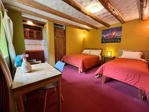 a room with two beds and a table in it at Pisac Inca Guest House in Pisac