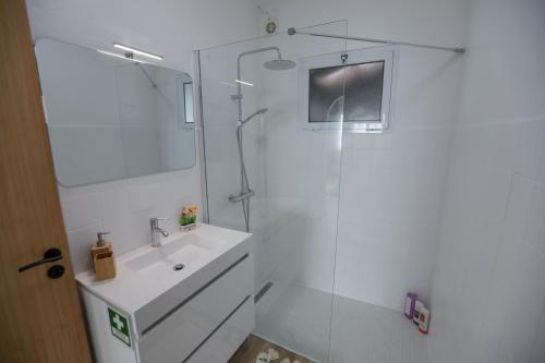 a white bathroom with a sink and a shower at Estrela do Atlântico in Ponta Delgada