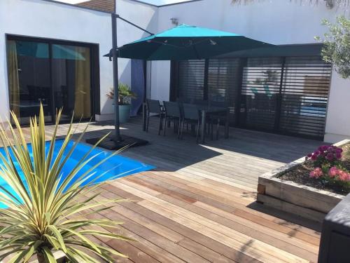 un patio avec un parasol, une table et des chaises dans l'établissement Villa Exceptionnelle Piscine et Jardin privé Séjour Haut de gamme proche La Rochelle, à Sainte-Soulle