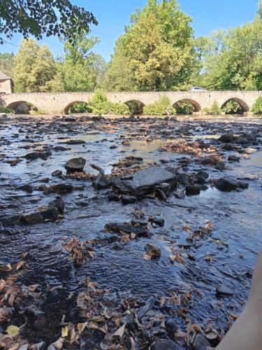 a river with rocks and a bridge in the background at Le 28 in Uzerche