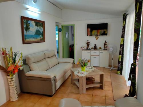 ein Wohnzimmer mit einem Sofa und einem Tisch in der Unterkunft Villa La Philomène - entre mer et montagne in Saint-Pierre