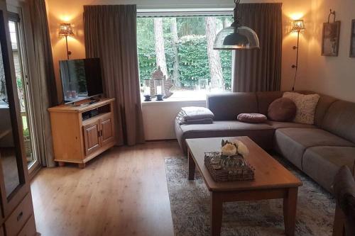 uma sala de estar com um sofá e uma mesa em Mooi chalet met grote tuin op een 4 sterren park. em Doornspijk