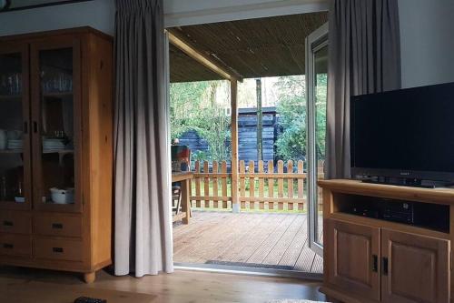 a living room with a sliding glass door to a deck at Mooi chalet met grote tuin op een 4 sterren park. in Doornspijk