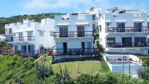 a large white building with balconies and a yard at Villa Orion in Arraial do Cabo