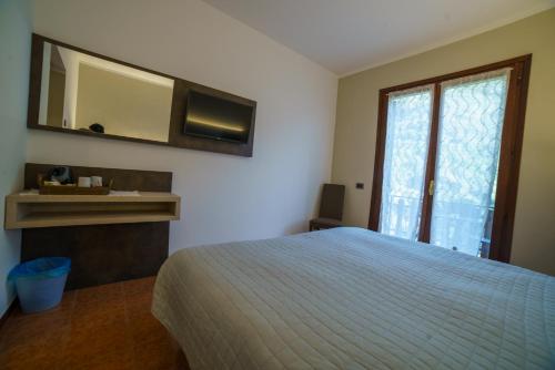1 dormitorio con cama, espejo y ventana en Hotel Lago Bin, en Rocchetta Nervina