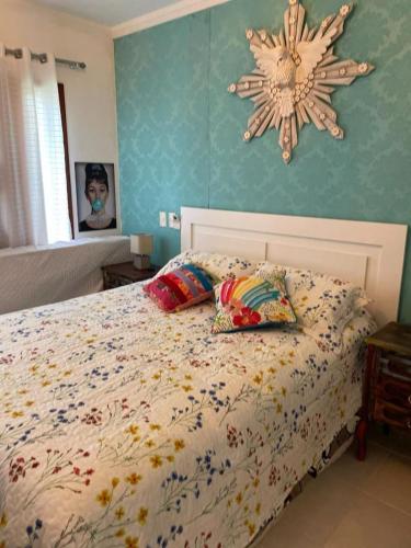a bedroom with a bed with pillows and a clock on the wall at Linda Casa Condomínio Maresias in Maresias