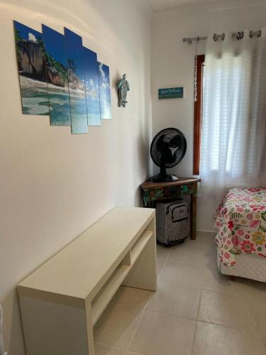 a room with a bench and a bed and paintings on the wall at Linda Casa Condomínio Maresias in Maresias