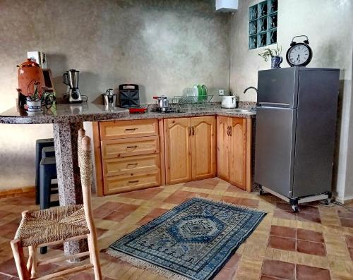 una cocina con nevera de acero inoxidable y armarios de madera en Surf guest house, en Mirleft