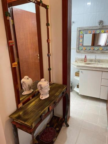 a bathroom with a wooden vanity with a mirror at Linda Casa Condomínio Maresias in Maresias