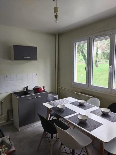 une cuisine avec une table, des chaises, une table et une fenêtre dans l'établissement Appartement à 15mn du centre ville de Rouen, à Canteleu