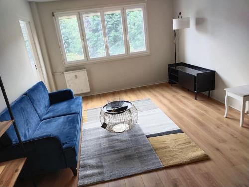 un salon avec un canapé bleu et une table dans l'établissement Appartement à 15mn du centre ville de Rouen, à Canteleu