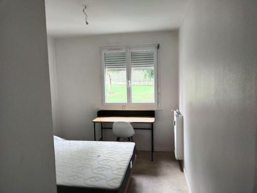 1 dormitorio con escritorio, 1 cama y ventana en Appartement à 15mn du centre ville de Rouen en Canteleu