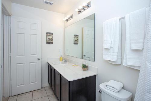 La salle de bains est pourvue d'un lavabo, d'un miroir et de toilettes. dans l'établissement Family Friendly 4 Bedrooms with GameRoom close to Disney in Compass Bay 5103, à Kissimmee