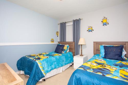 1 dormitorio con 2 camas y edredones azules en Family Friendly 4 Bedrooms with GameRoom close to Disney in Compass Bay 5103, en Kissimmee