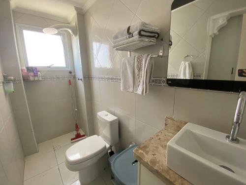 ein Badezimmer mit einem weißen WC und einem Waschbecken in der Unterkunft Apto Vista Mar Varanda Gourmet in Praia Grande