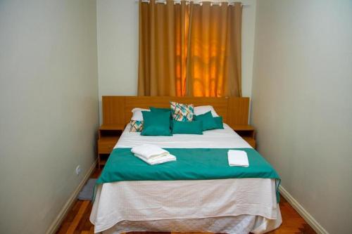 a bedroom with a large bed with green pillows at Hotel Casa Branca in Uruguaiana