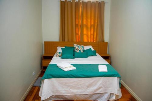 sypialnia z dużym łóżkiem i zielonymi poduszkami w obiekcie Hotel Casa Branca w mieście Uruguaiana