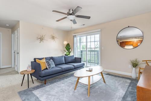 a living room with a blue couch and a ceiling fan at ConTemporary Stay in Central Peoria in Peoria