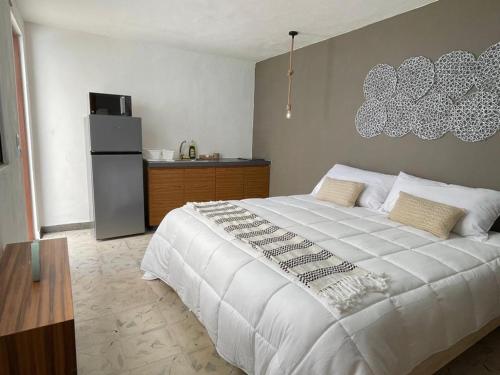 a bedroom with a large white bed and a refrigerator at Aldeazul by Andiani Travel in Cancún