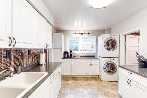 a kitchen with white cabinets and a washer and dryer at The Perfect Sandpoint Rental in Sandpoint