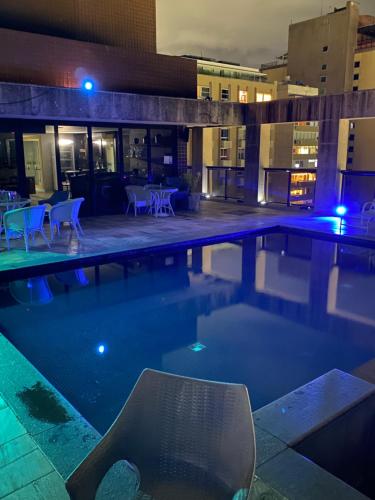 a swimming pool at night with a table and chairs at Flat Vieira Souto Vista Mar in Rio de Janeiro