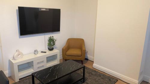 a living room with a chair and a television on a wall at POTTERS LODGE by Edl Ventures Ltd in Manchester