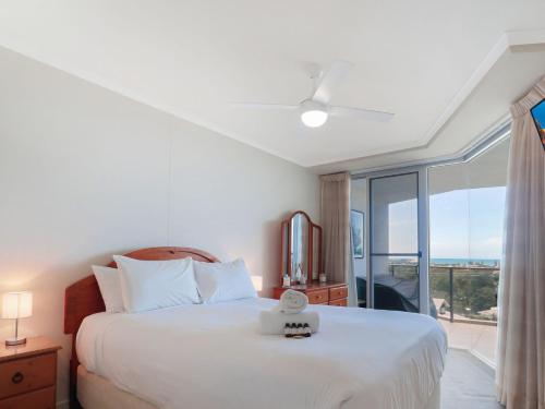 a bedroom with a large white bed and a balcony at Points North in Caloundra