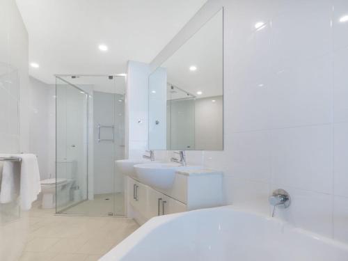 a white bathroom with two sinks and a mirror at Points North in Caloundra