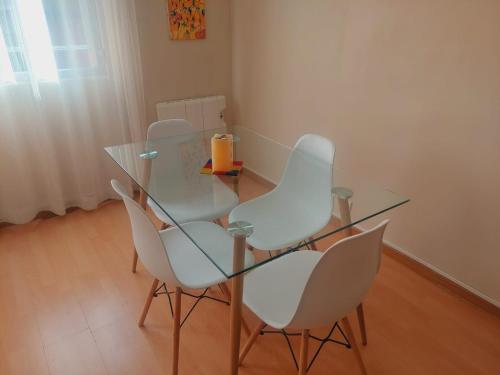 una mesa de cristal y 4 sillas blancas en una habitación en Apartamento Ideal, en Madrid