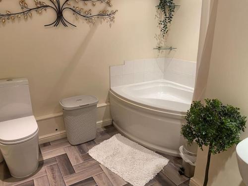 a bathroom with a tub and a toilet and a sink at Fabulous Spacious Bungalow in Solihull close to Bham Airport NEC & Bham City Centre in Knowle