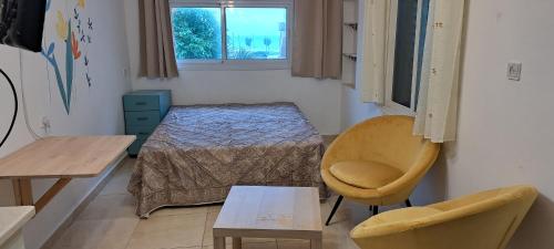 um quarto com uma cama, uma cadeira e uma mesa em הרוגע שלי בבית רובינזון em Nahariya