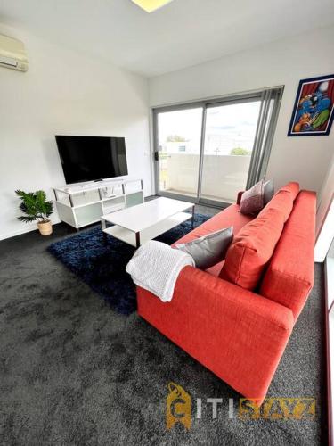 a living room with a red couch and a tv at Bold in Bruce - 1bd 1bth 1csp in Belconnen