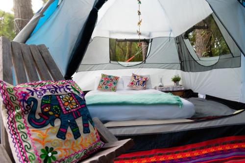 a bed in a tent with a pillow and a chair at OM B&B + Spa in Viamão