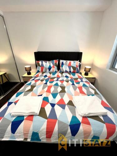 a bedroom with a colorful bed with two night stands at Bold in Bruce - 1bd 1bth 1csp in Belconnen
