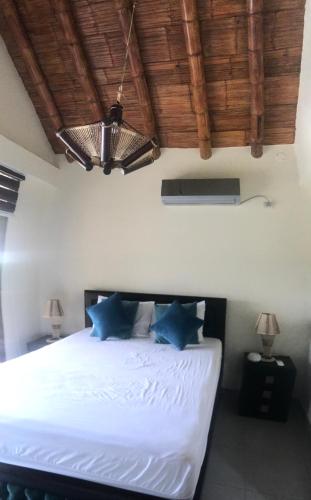 1 dormitorio con cama blanca y almohadas azules en CAMPO y PLAYA OLON HACIENDAS, en Olón