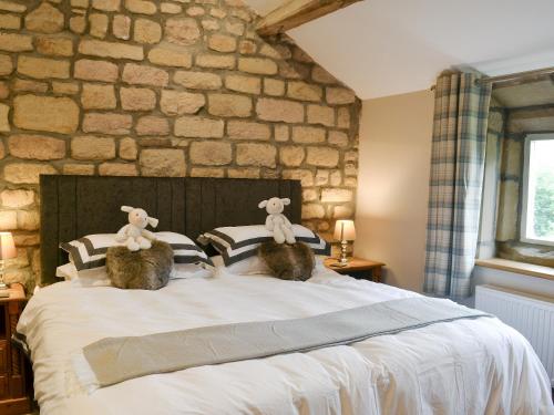 two stuffed animals sitting on top of a bed at Little Grans Cottage in Cowling